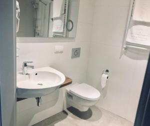 罗兹Abton Hotel的白色的浴室设有水槽和卫生间。