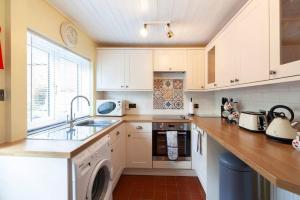 约克Ceilidh Cottage的厨房配有白色橱柜、水槽和洗碗机。