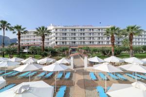 卡拉莫斯Calamos Beach Family Club的一座拥有游泳池、遮阳伞和棕榈树的酒店