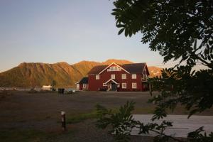 AlsvågToftenes Sjøhuscamping的一座大红色房子,后面有群山