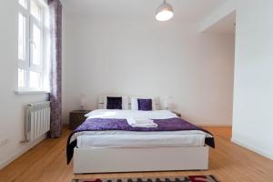 阿斯塔纳The Arc Residence的白色卧室配有一张带紫色床单的大床