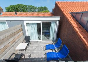 韦斯特卡佩勒Holiday Home Zuidstraat 30B的庭院配有蓝色的椅子、桌子和白色的桌子
