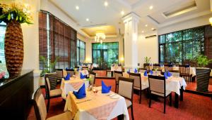 暹粒塔拉吴哥酒店的餐厅设有白色的桌椅和窗户。