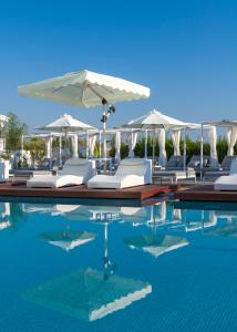 普罗塔拉斯The Blue Ivy Hotel & Suites的一个带白色躺椅和遮阳伞的游泳池