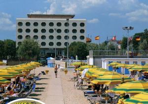 切塞纳蒂科Hotel San Pietro的海滩上有许多椅子和遮阳伞,还有一座建筑