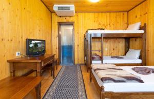 KravenikGuest Houses Apriltsi的客房设有两张双层床、一张桌子和一台电视。