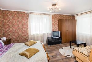 秋明Apartment on 50 let Oktyabrya 51 TyumGNGU的一间卧室配有一张床、一台电视和一张沙发