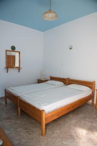米尔泰Avra Studios的白色墙壁的客房内的一张木床