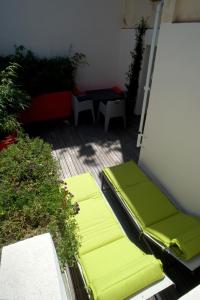 里昂卡努兹别墅酒店的一个带绿色靠垫、桌子和长凳的庭院