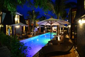 芭东海滩Bukit Pool Villas - SHA Extra Plus的游泳池在晚上提供椅子和遮阳伞