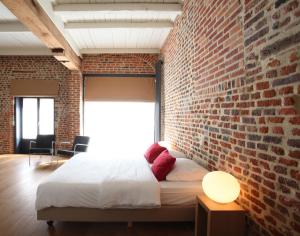 鲁汶海弗利洛奇酒店的砖墙卧室,配有一张床和一个窗户