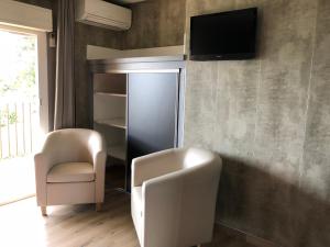加莱里亚斯特拉海滨酒店的客厅配有两把椅子和墙上的电视