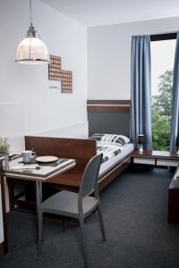 朗斯多夫Triumph Inn Pension的一间卧室配有一张床和一张桌子及椅子