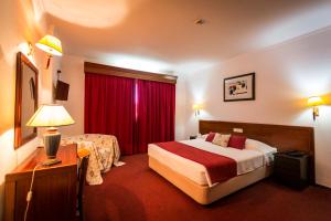 塞图巴尔阿兰格斯酒店的酒店客房,配有床和红色窗帘