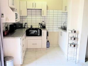姆通济尼102 Siyayi的小厨房配有白色橱柜和微波炉
