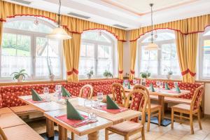 特翁盖尔酒店的餐厅设有木桌、椅子和窗户。