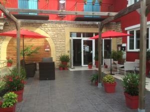尚塞拉德德拉贝隆酒店的一个带红色遮阳伞和桌椅的庭院