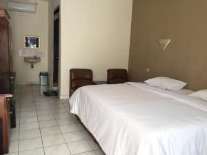 沃诺索博Parama Hotel的卧室配有一张白色大床和两把椅子