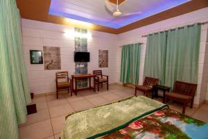 贾朗达尔National Guest House的一间卧室配有一张床铺和椅子以及一台电视。