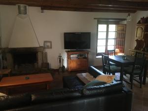 圣苏珊娜Masia Can Ninot的客厅配有黑色真皮沙发和电视