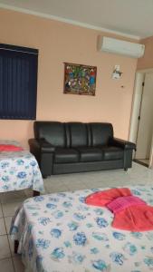 博拉塞亚Pousada Pesque Park的客厅配有真皮沙发和两张床