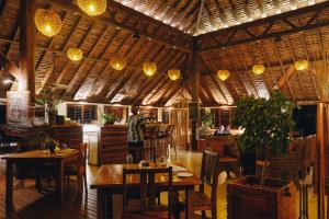 塔纳岛白草海洋度假酒店及Spa的餐厅设有木桌和椅子及灯