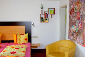 图特林根Donau Pension的一间卧室配有一张床和一张黄色椅子