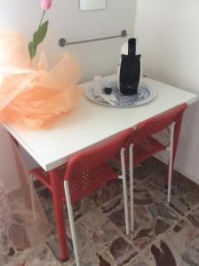比萨朱利亚茵住宿加早餐旅馆的一张带两把红色椅子的白色桌子和茶壶