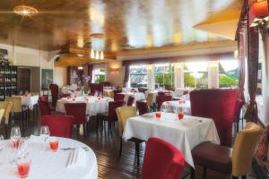 La CoquilleLogis Hôtel-Restaurant Les Voyageurs的用餐室配有白色的桌子和红色的椅子