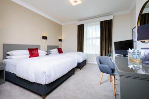 科克The Metropole Hotel Cork的酒店客房设有两张床和电视。