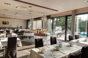 罗维尼阿鲁宾努酒店的餐厅设有白色的桌椅和窗户。