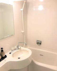 新宫市格兰大酒店的白色的浴室设有水槽和浴缸。