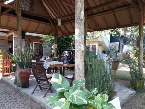 努沙杜瓦Manuh Guest House的户外庭院配有桌椅和植物。