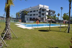 桑卢卡尔-德巴拉梅达Residencial Costa Doñana (Sanlucar de Barrameda)的一座公园内的游泳池,位于大楼旁