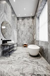 哥本哈根Nobis Hotel Copenhagen, a Member of Design Hotels™的带浴缸和大型大理石墙的浴室。