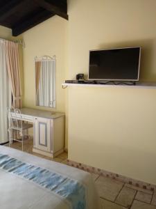 Portu Maga科尔萨罗尼禄酒店的一间卧室配有一张床、一张书桌和一台电视。
