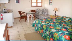棕榈滩阿鲁巴岛海滩别墅酒店的一间卧室配有一张床铺和一张桌子,还设有一间厨房