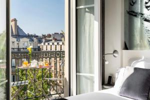 巴黎Hotel Marais Grands Boulevards的客房设有一张床和一个带桌子的阳台