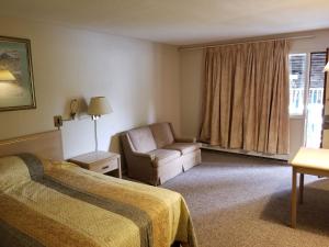 威廉斯莱克Slumber Lodge Williams Lake的酒店的客房 - 带一张床、椅子和窗户