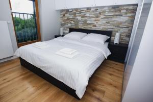 克拉科夫Apartament "Park Lotników"的卧室配有一张白色大床和砖墙