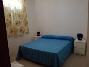 米内尔维诺迪莱切Appartamento Mare e Sole的一间卧室配有一张带蓝色床单的床和一扇窗户。