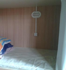 普腊亚罗萨Hostel Quintal do Rosa的木墙客房的一张床位