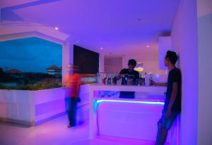 克罗柏坎德瓦巴厘岛公寓式酒店的两个人站在一个紫色灯的酒吧
