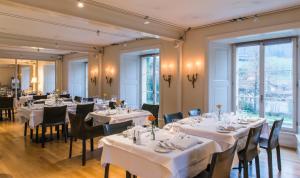 穆尔滕宫明兴维勒酒店的餐厅设有白色的桌椅和窗户。