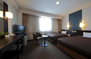 高知高知播磨屋西铁酒店的酒店客房配有一张床、一张桌子、一张床和一台电视。