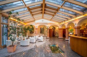 帕绍中庭盖尔尼酒店的大堂设有玻璃天花板、白色椅子和植物