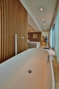 阿尔贝纳火烈鸟超豪华酒店及Spa的配有床的客房内的白色大浴缸