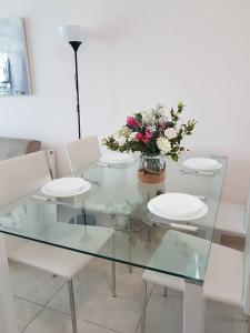 利马索尔玛丽安娜酒店式公寓 的一张带白色椅子和花瓶的玻璃桌