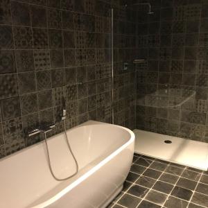 赫尔De Worfthoeve的浴室铺有瓷砖地板,配有白色浴缸。