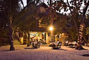 马拉帕斯加Angelina Beach Resort & Italian Restaurant Malapascua的一间晚上在海滩上带桌椅的餐厅